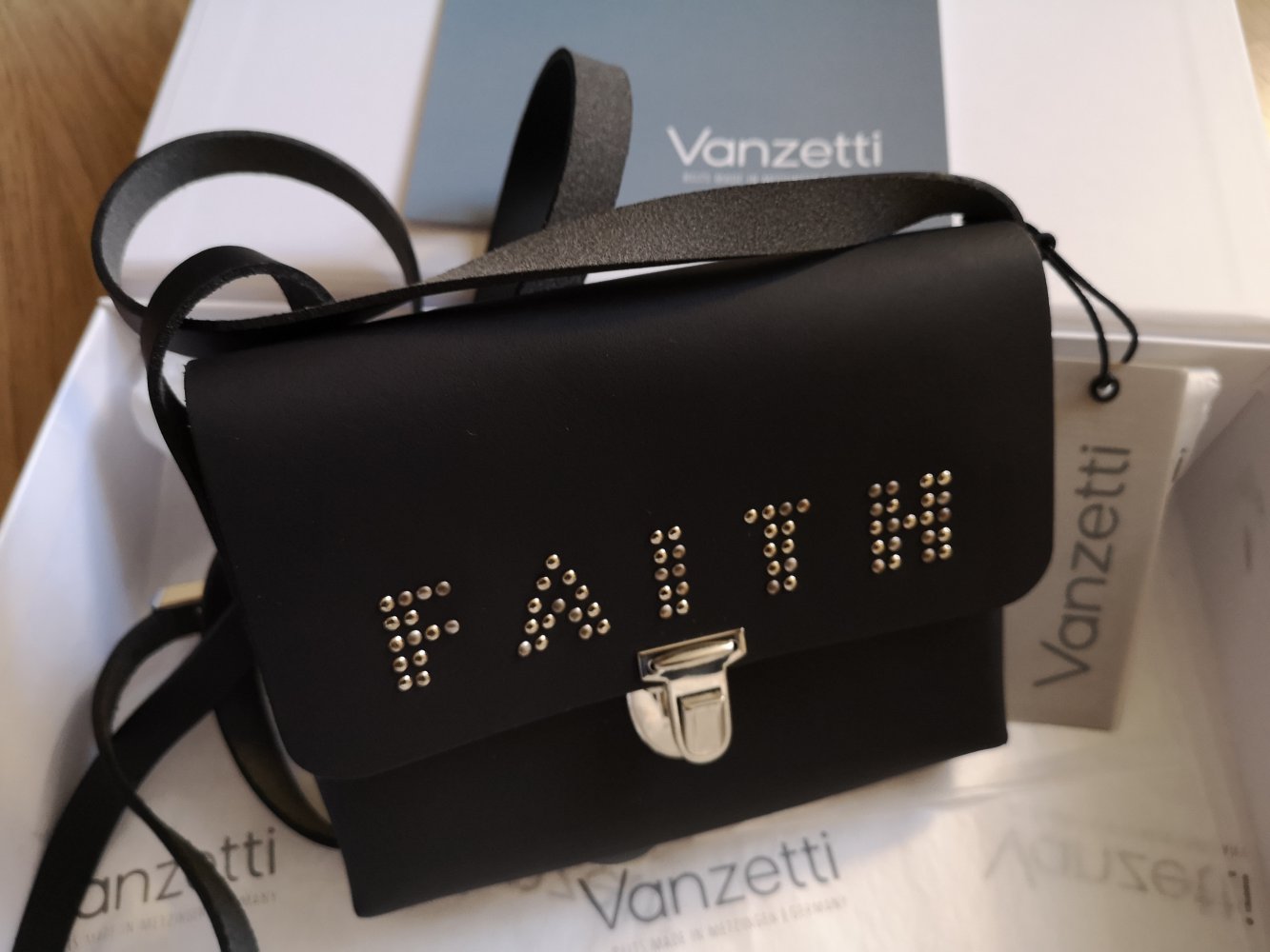 schwarze Schultertasche mit der Aufschrift Faith