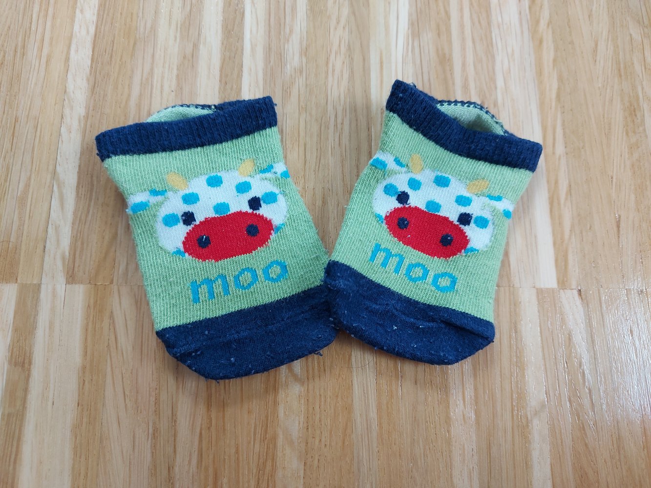 grünblaue Babysöckchen mit Kuh-Motiv 