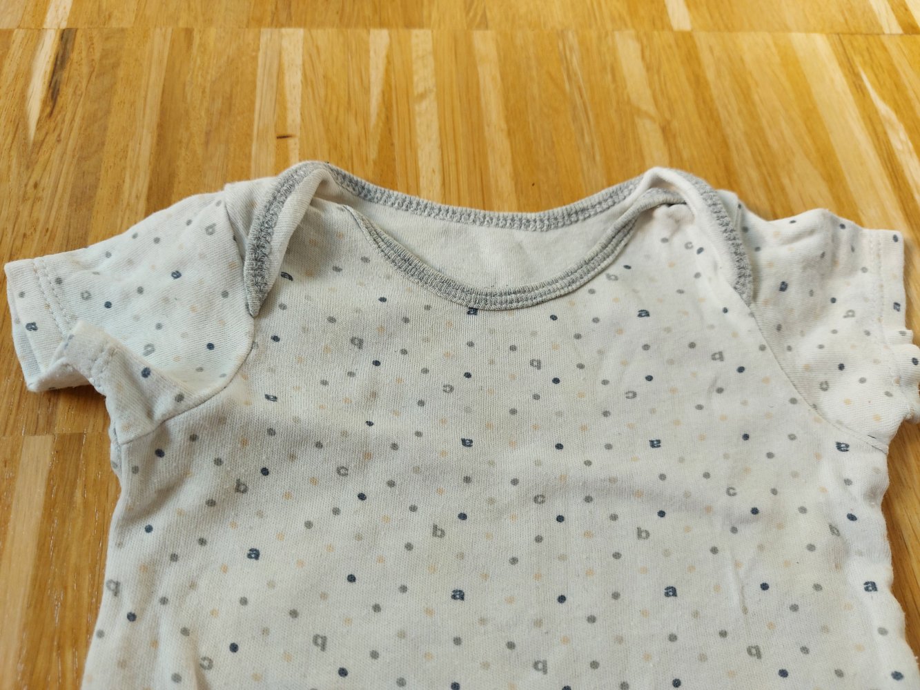 Kurzärmliger weißer Babybody mit Punkten und Buchstaben